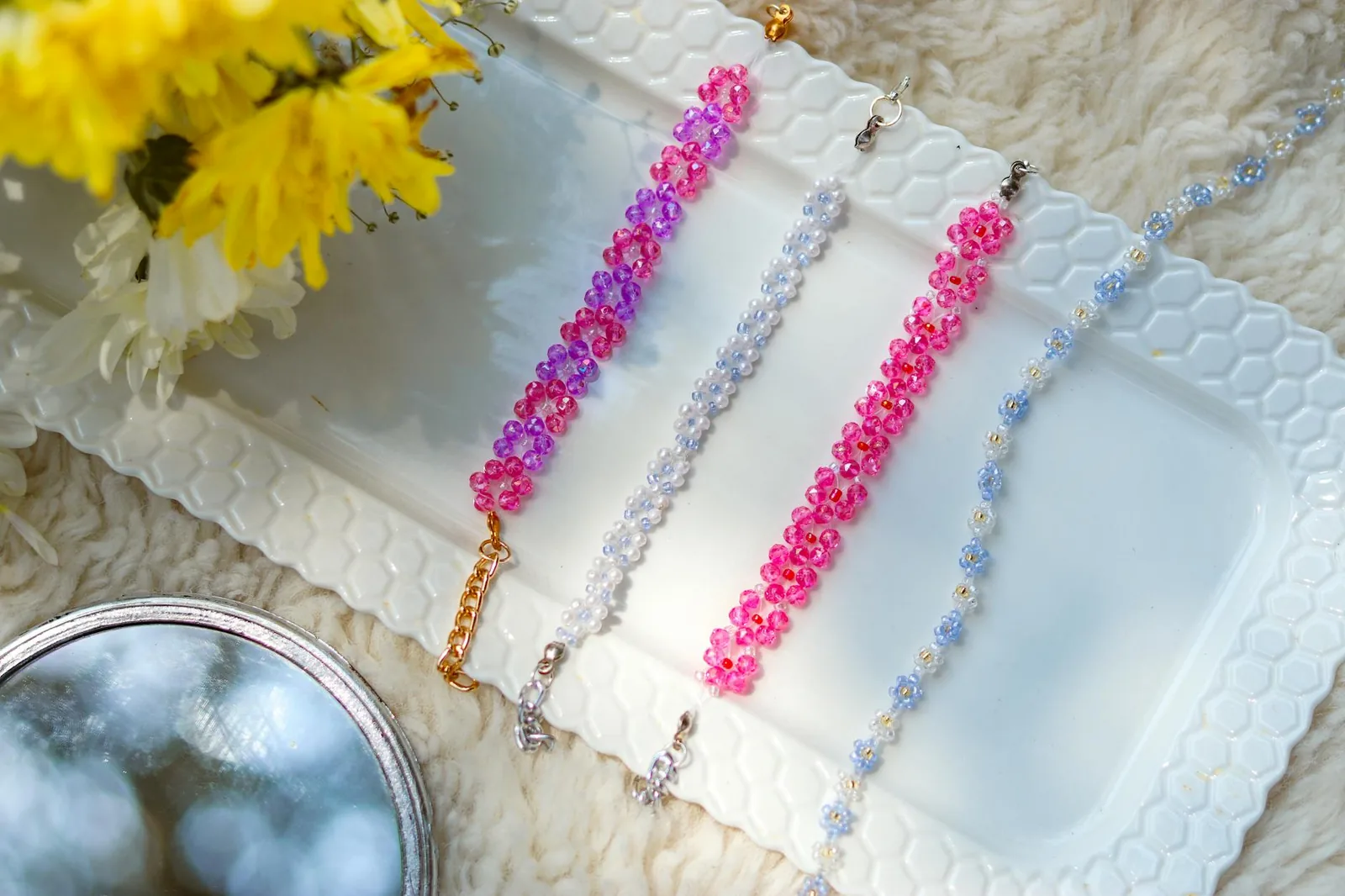 A vivid array of bead bracelets on a white tray with flowers. Perfect for fashion and lifestyle themes.