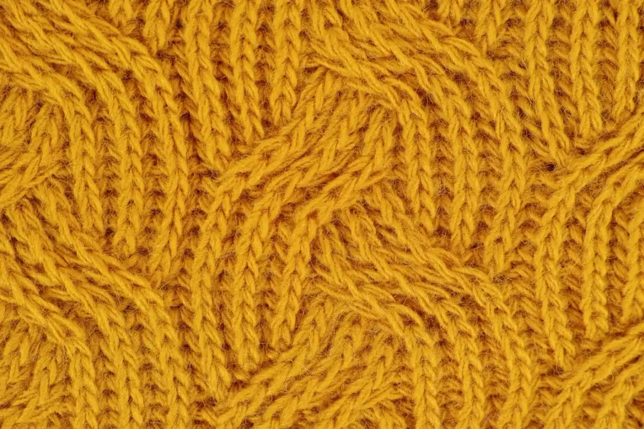 Detailed close-up of a yellow knitted wool pattern, ideal for textile design.