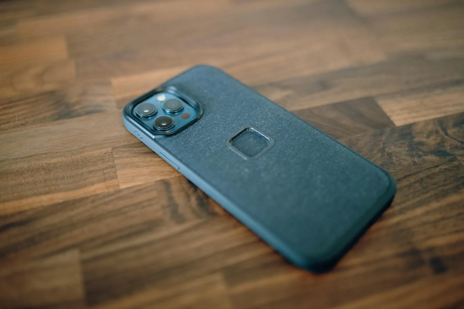 A close-up shot of a smartphone with a protective case, placed on a wooden surface.