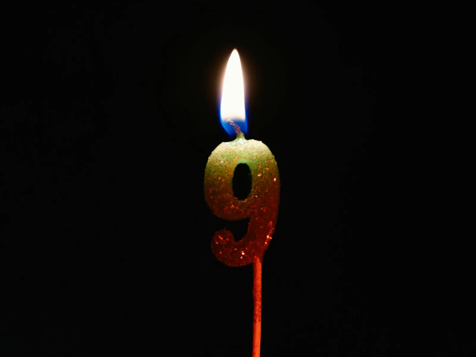 Burning number nine candle against a dark backdrop, perfect for birthdays or anniversaries.