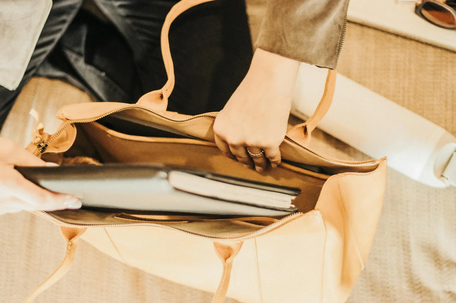 An elegant leather tote bag containing a laptop and notebook, perfect for travel or business use.